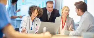 a mixed group of healthcare professional and business people meet around a conference table .