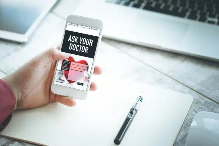 Hand holding smartphone and showing Ask Your Doctor page