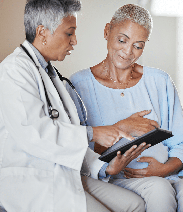 Female doctor holding a tablet and going over the answers to FAQs with her patient, standing next to her.