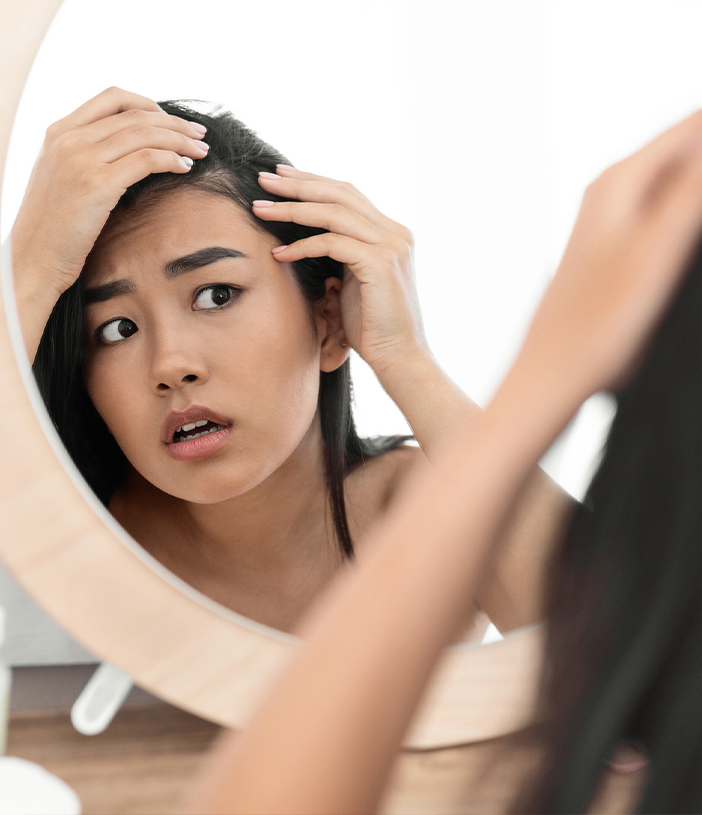 Young woman coming her straight hair using a small wooden comb.