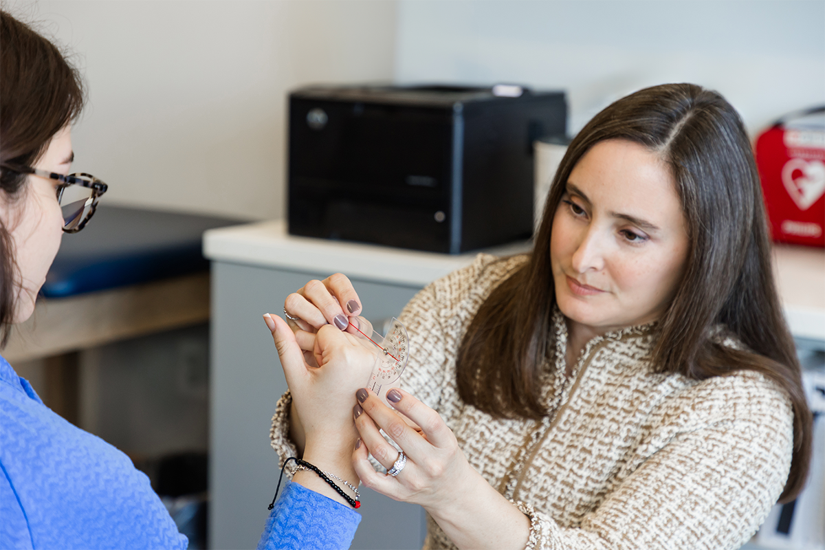 Hand therapist examining the angles of her patient's fingers using a protractor too.