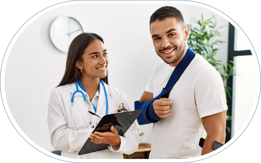 Young female doctor with a clipboard and pen smiling at her patient who is also smiling with a sling around his arm and shoulder.