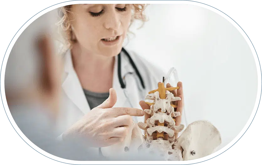 Female doctor explaining a spinal condition to her patient while using a model of a spine as a reference.
