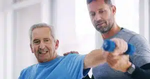 An elderly person is undergoing physiotherapy, while a man in an office is doing rehabilitation exercises for shoulder arthritis.